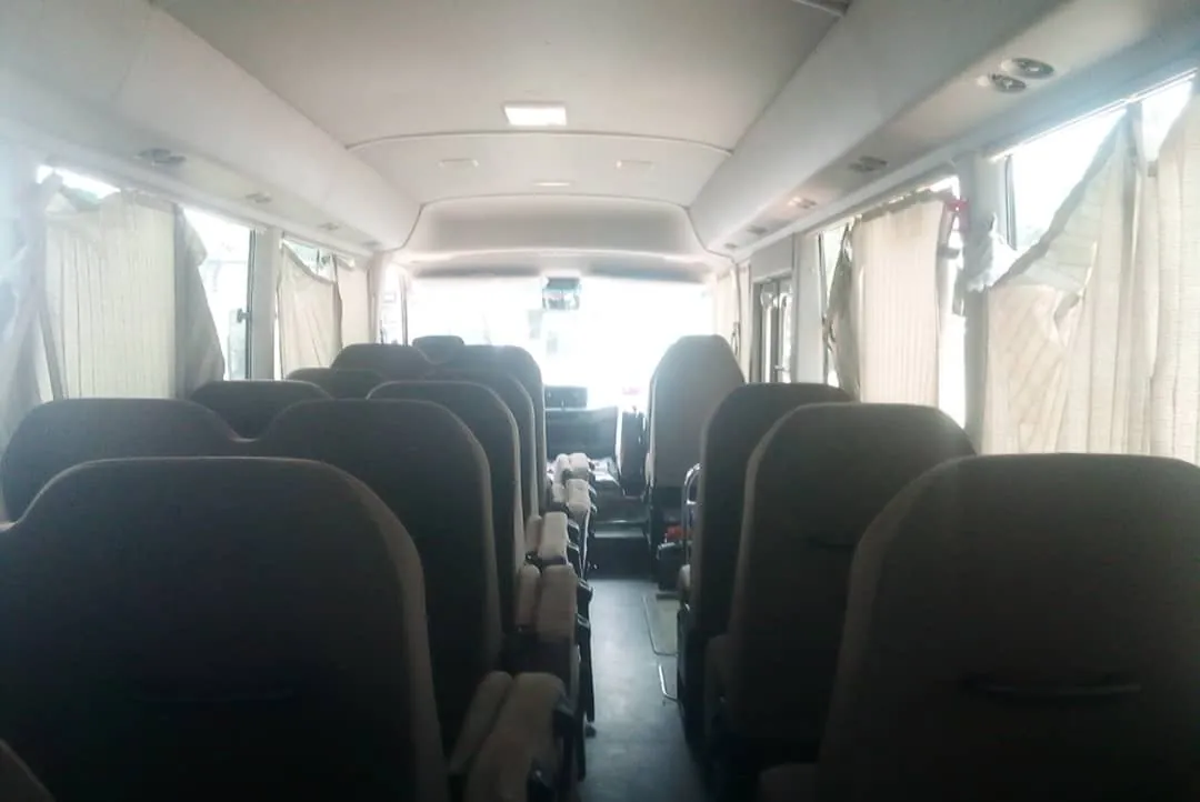 Toyota Coaster interior looking down the aisle between rows of passenger seats