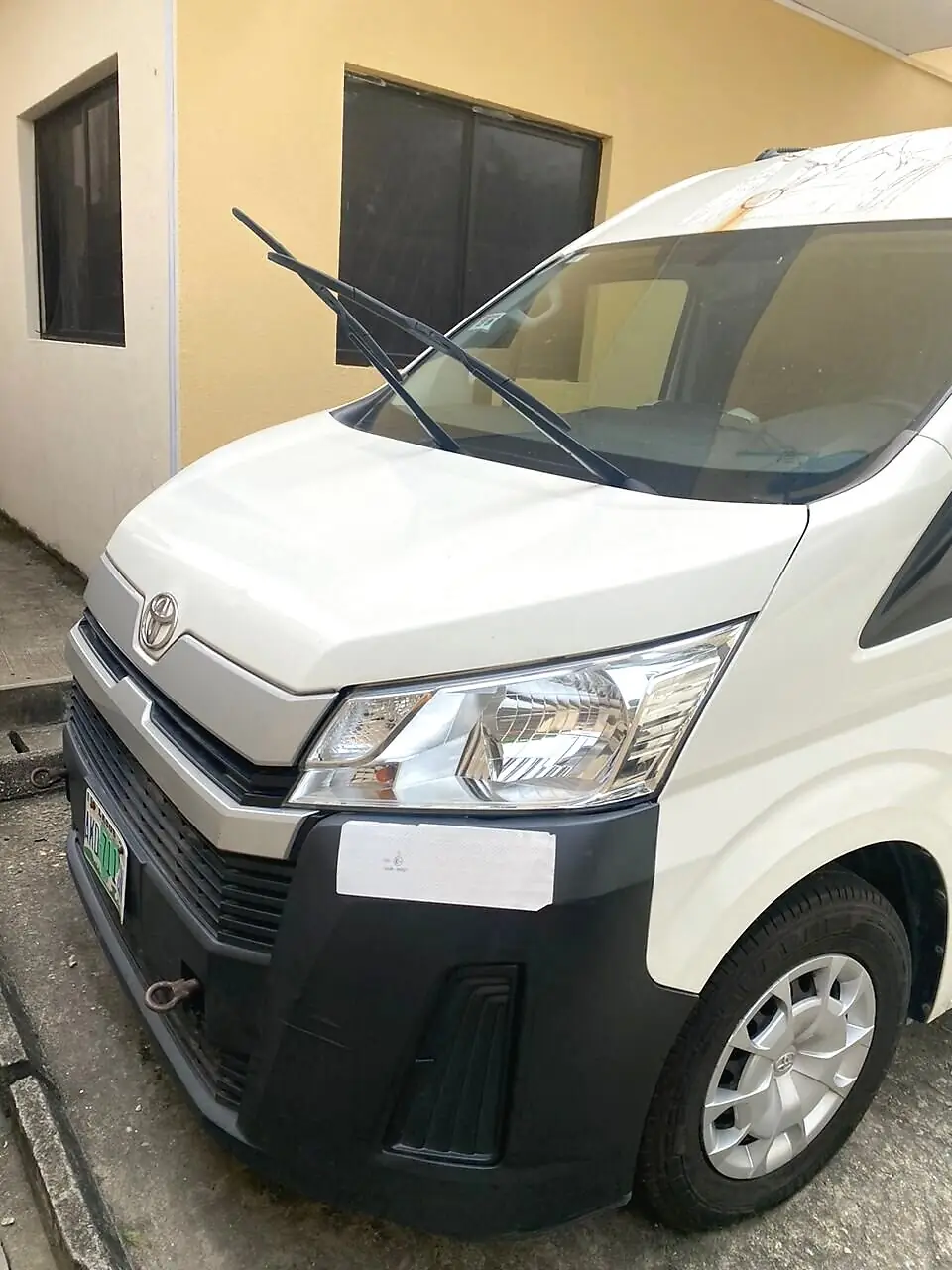 Front view of the Hiace bus parked outside a building, available for Hiace rental in Ikeja, Lagos